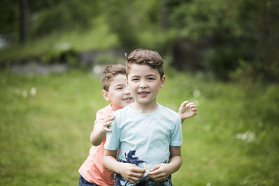 Portrait of boy with playful brother standing in back yard