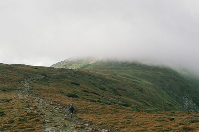 Man hiking on mountain during foggy weather