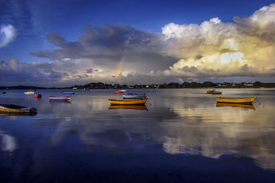 Boats moored in sea against sky at sunset