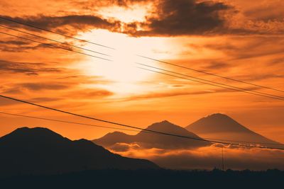 Low angle view of silhouette mountains against orange sky