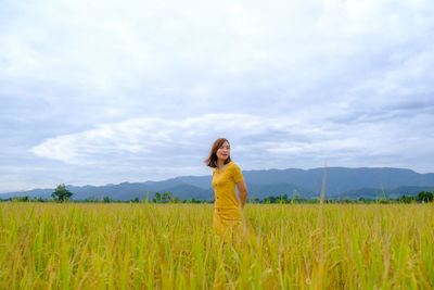 Woman looking away while standing in field