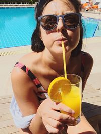 Portrait of man drinking glass in swimming pool