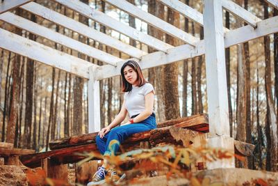 Portrait of young woman sitting on wood