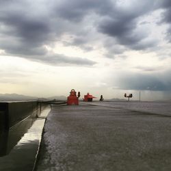 Pier on sea against cloudy sky