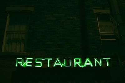 Low angle view of illuminated sign on building at night