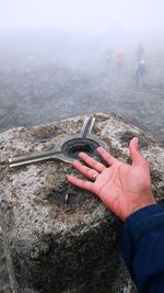 Close-up of man holding hands with mountain in background