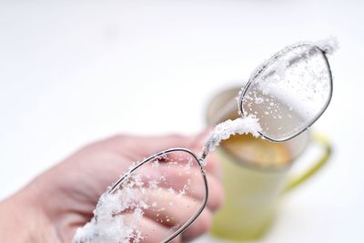 Cropped hand holding snow covered eyeglasses