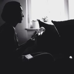 Side view of woman filling syringe while sitting at home