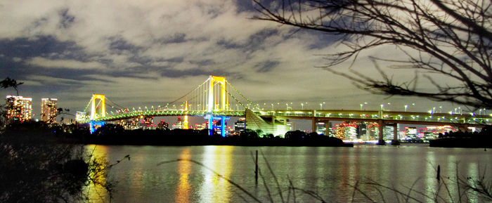 Illuminated bridge over river at night