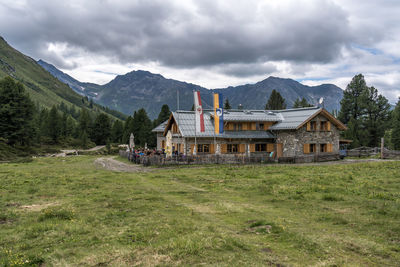 Houses on field by mountains against sky