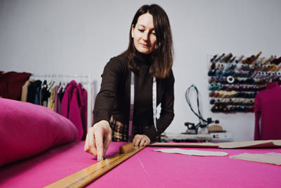 Female fashion designer tailor making sewing patterns at workplace in sewing studio. seamstress