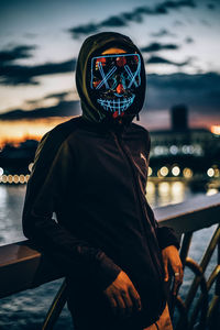 Portrait of man standing in city against sky during sunset