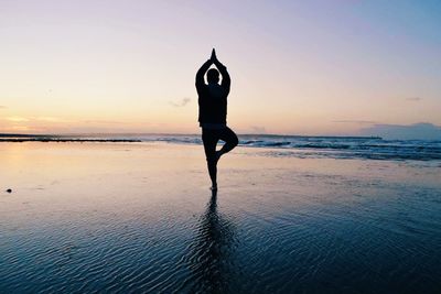 Man doing the tree pose on beach