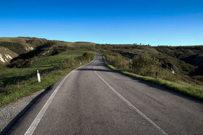 Road amidst landscape against clear blue sky