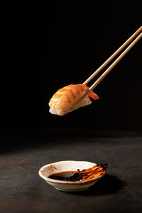 Shrimp sushi with chopsticks over dark background