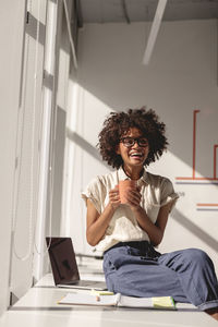 Young woman using mobile phone while sitting on sofa at home