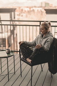 Young woman looking away while sitting on table