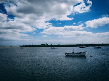 Sailboats moored on sea against sky