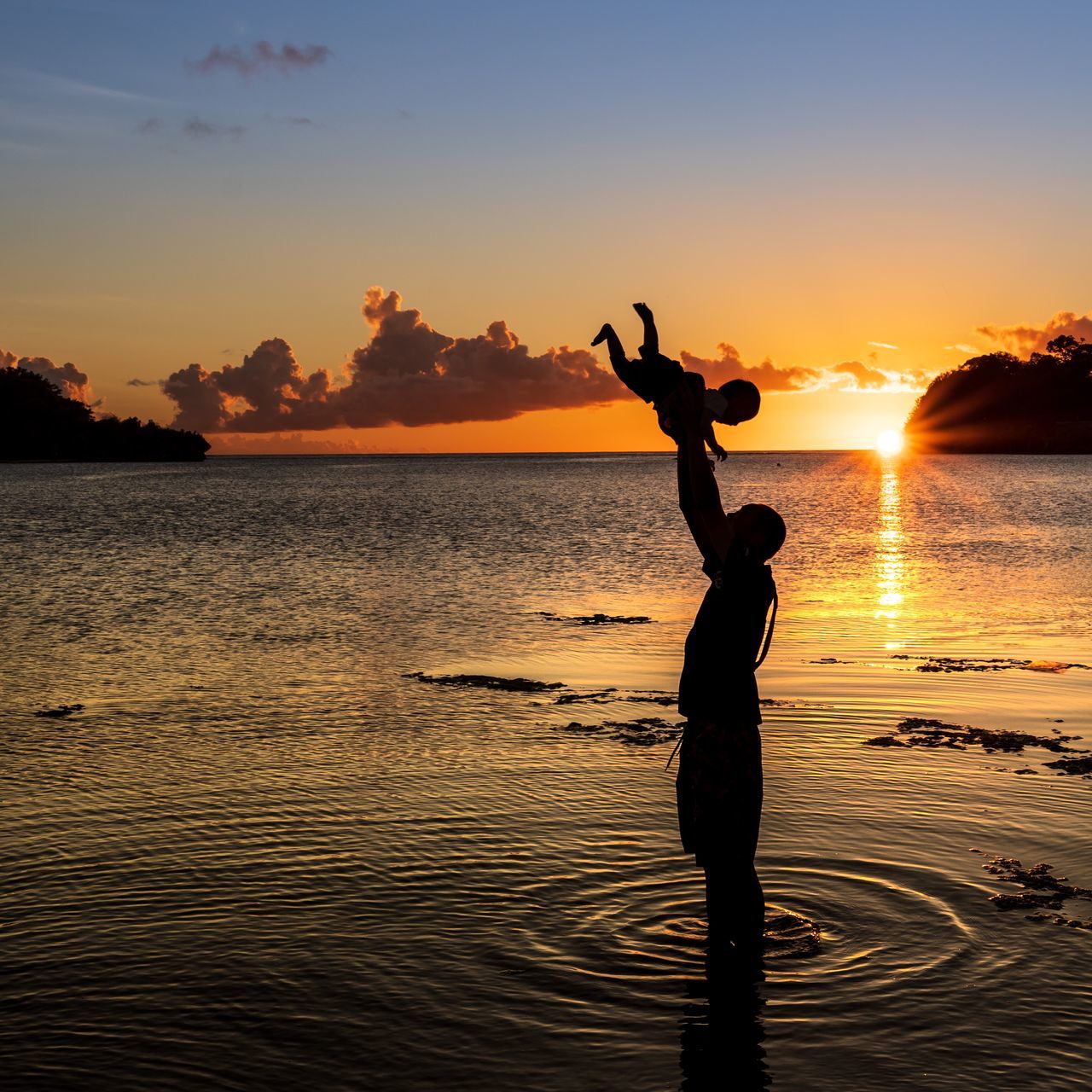 sunset, sky, water, silhouette, beauty in nature, real people, lifestyles, one person, beach, standing, orange color, scenics - nature, land, leisure activity, sea, tranquility, nature, full length, arms raised, human arm, sun, outdoors