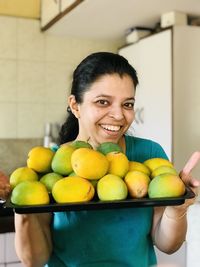 Portrait of smiling woman holding fruits