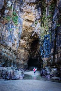 Woman in river under rock formation in cave