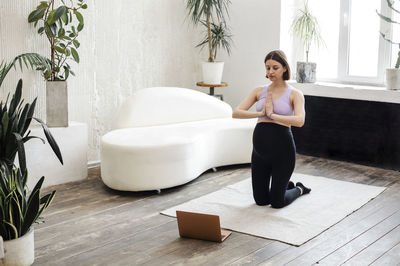 Rear view of woman sitting on bed at home