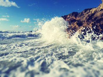 Waves splashing on sea against sky