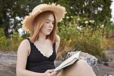 Woman wearing straw hat reading book