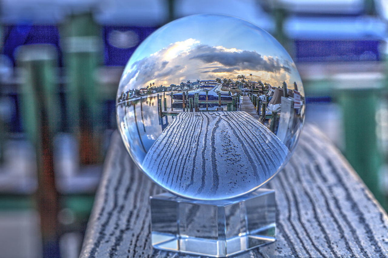 CLOSE-UP OF CRYSTAL BALL ON METAL GLASS AGAINST CITY