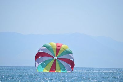 Multi colored parachute in sea against sky