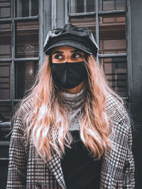 Portrait of young woman standing against wall