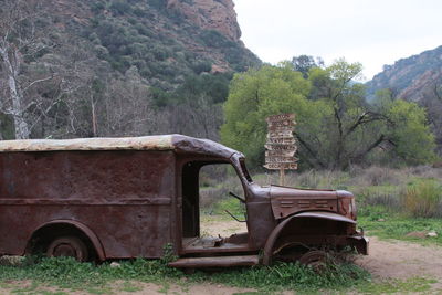 Abandoned tractor on field against trees