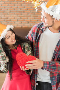 Man giving heart shape gift to girlfriend during christmas party