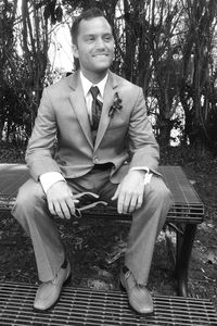 Happy groom sitting on bench at park