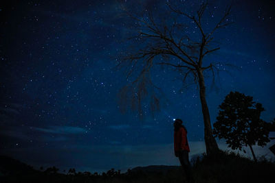 Low angle view of silhouette woman standing on field against starry sky