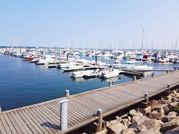 Sailboats moored at harbor against clear blue sky