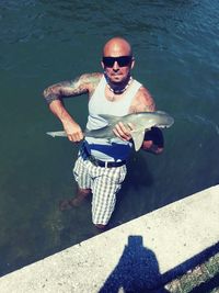 High angle portrait of man holding fish in sea