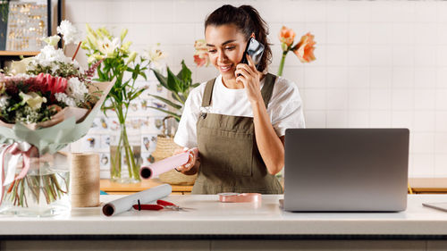 Young woman using mobile phone while standing on table