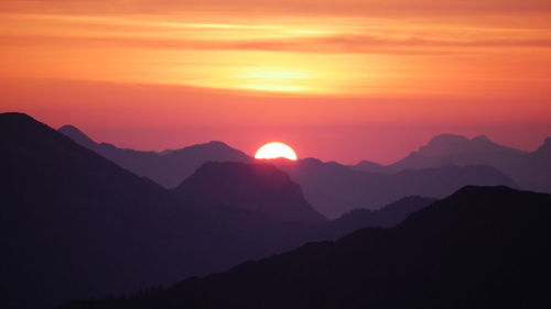 Scenic view of silhouette mountains against romantic sky at sunset