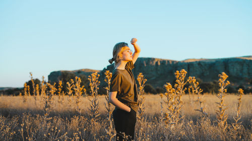 Woman standing on field against clear sky