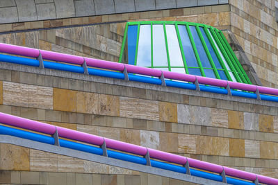 Full frame shot of pink pipe railing and steel-framed windows against neutral masonry wall