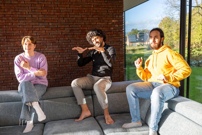 Friends using mobile phone while sitting on sofa at home