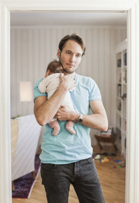 Thoughtful man carrying baby at doorway