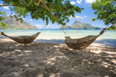 Lounge chairs on sand at beach against sky