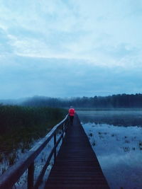 Rear view of person standing on pier against sky