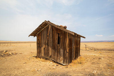 Wooden hut on beach against sky