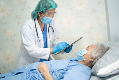 Doctor wearing mask examining patient at hospital