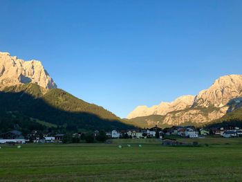 Scenic view of field and mountains against clear blue sky