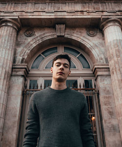 Portrait of young man standing against building