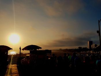 Silhouette people by sea against sky during sunset